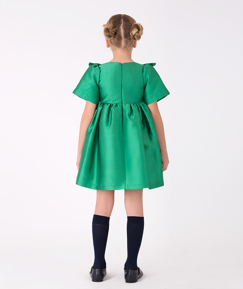 Festive green dress for girls with metallic accents – Charming dress with a large metallic bow and ruffle detailing, creating a vibrant and chic outfit.
