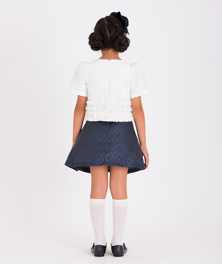 Chic children's fashion ensemble with a white floral top and navy skirt