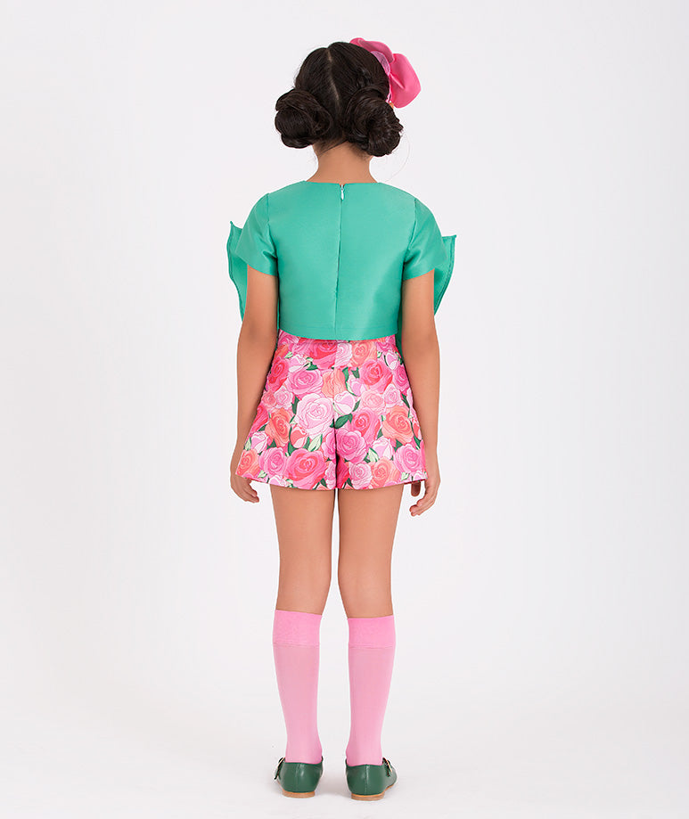 a mint blouse shaped like a bow and pink rose-printed shorts